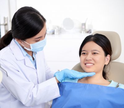asian-female-dentist-checking-out-patient-s-teeth-woman-smiling.jpg